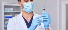 врач в медицинской маске со шприцем 